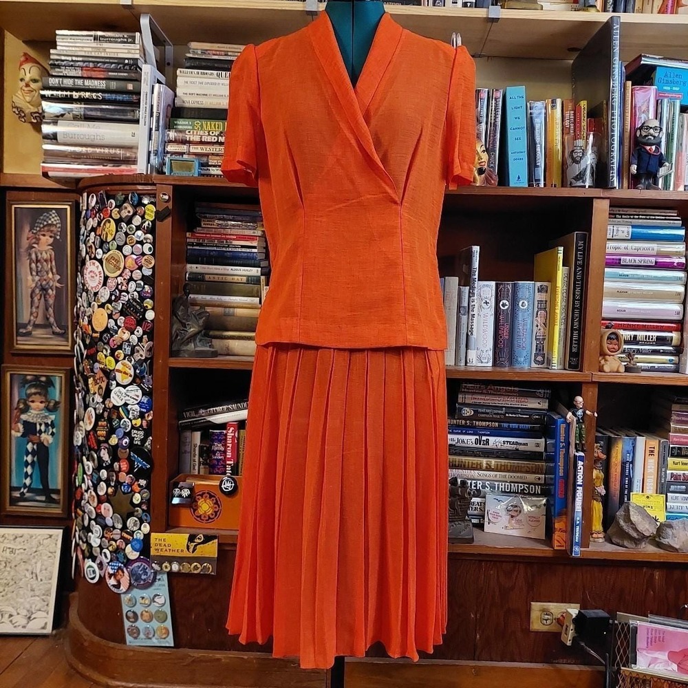 Vintage orange matching skirt set with shoulder pads and pleated skirt.